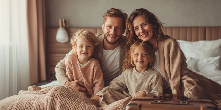 Glückliche Familie mit Kindern im Hotel nach einer Reise, Koffer im Vordergrund.